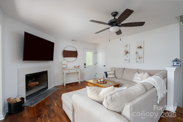 living area featuring baseboards, a ceiling fan, wood finished floors, and a fireplace