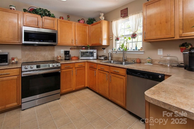 5127 Fernhill Dr, Charlotte, NC 28217 - kitchen featuring a toaster, light tile patterned floors, light countertops, appliances with stainless steel finishes, and a sink