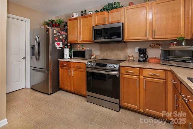 5127 Fernhill Dr, Charlotte, NC 28217 - kitchen with a textured ceiling, light countertops, stainless steel appliances, brown cabinets, and a toaster