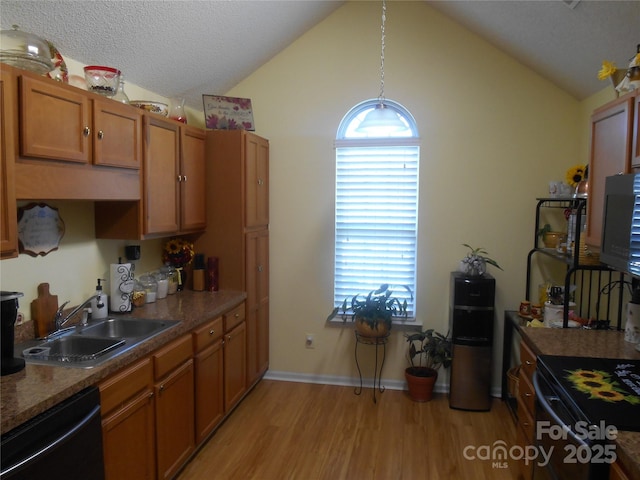 kitchen with a sink, dishwashing machine, brown cabinetry, vaulted ceiling, and light wood-style flooring