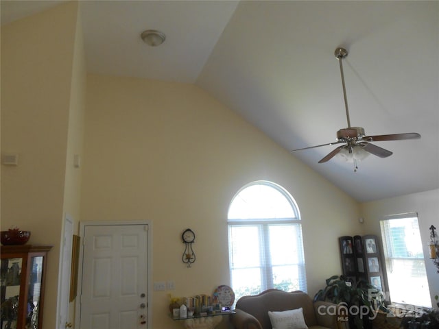 living area with high vaulted ceiling, ceiling fan, and plenty of natural light