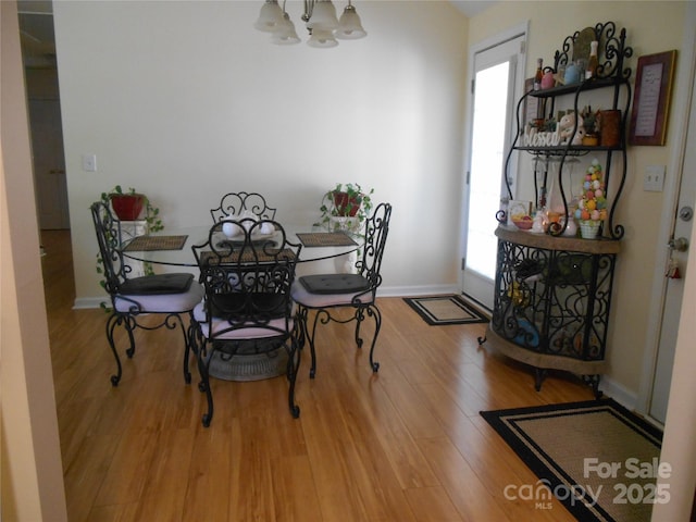 dining area with a chandelier, baseboards, and wood finished floors