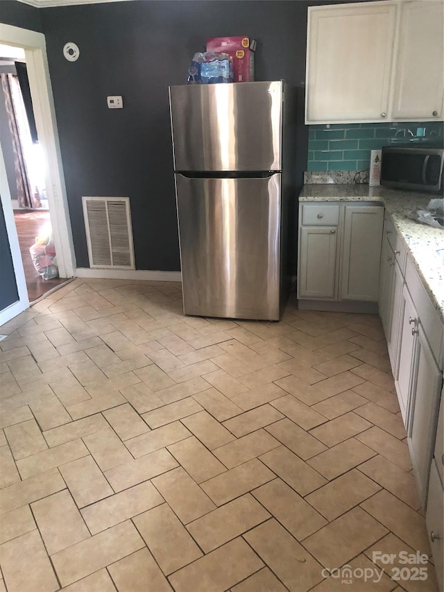 401 Plymouth St, Kannapolis, NC 28083 - kitchen featuring freestanding refrigerator, light tile patterned floors, light stone countertops, visible vents, and backsplash