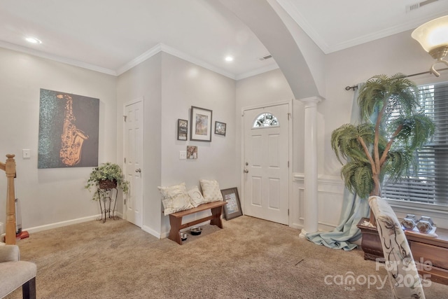 entrance foyer with crown molding, carpet flooring, ornate columns, and arched walkways