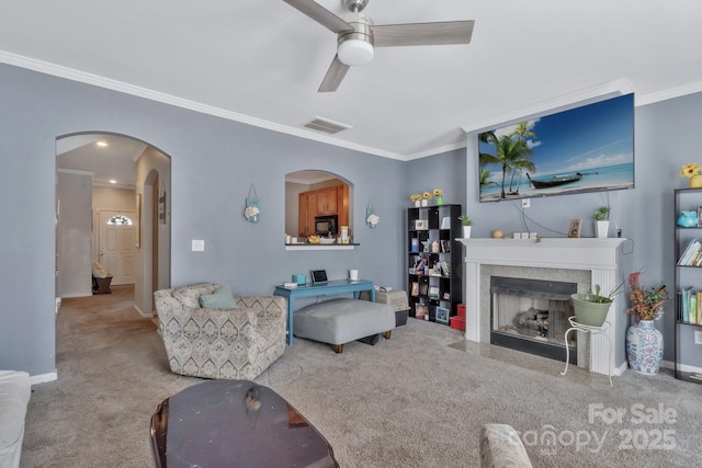 living area with visible vents, arched walkways, ceiling fan, carpet, and crown molding