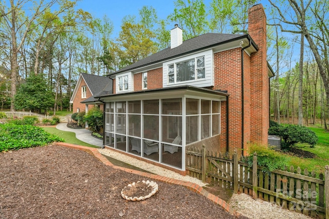 5750 Hemby Rd, Matthews, NC 28104 - rear view of house featuring brick siding, fence, a chimney, and a sunroom