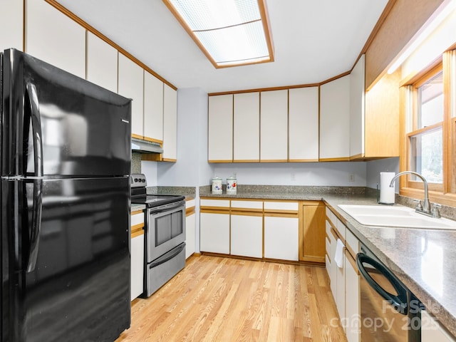 kitchen with light wood-style flooring, white cabinetry, black appliances, under cabinet range hood, and a sink