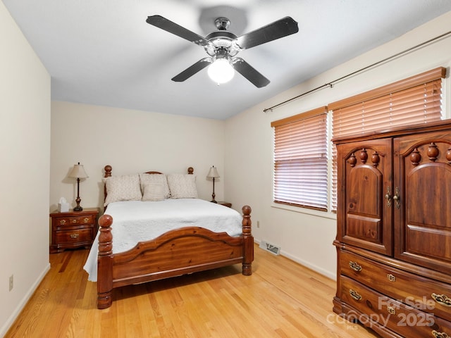 bedroom featuring light wood finished floors, visible vents, baseboards, and ceiling fan