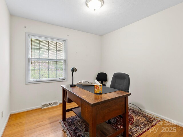 home office featuring light wood finished floors, baseboards, and visible vents