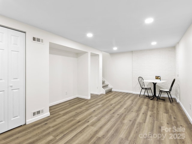 finished below grade area with wood finished floors, visible vents, and stairs