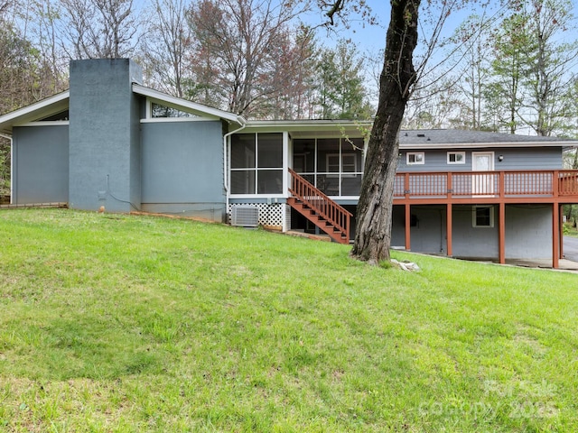 rear view of property featuring stucco siding, a sunroom, and a lawn