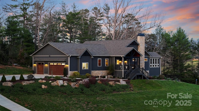view of front of property with concrete driveway, a chimney, stone siding, a front yard, and a garage