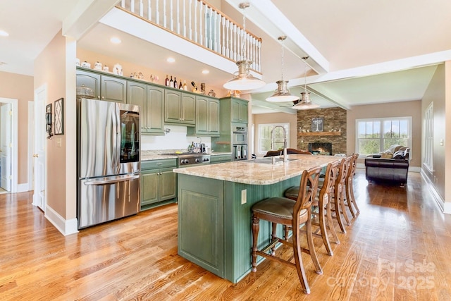 1151 Trull Hinson Rd, Wingate, NC 28174 - kitchen featuring stainless steel appliances, green cabinetry, light wood finished floors, open floor plan, and light stone countertops