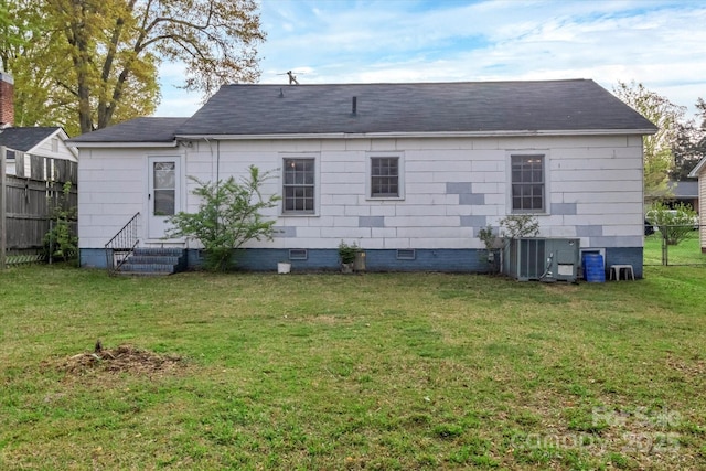 rear view of house with central AC unit, entry steps, a yard, crawl space, and fence