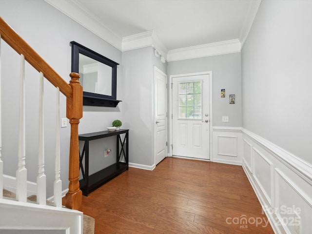 entrance foyer with ornamental molding, stairs, wainscoting, and wood finished floors
