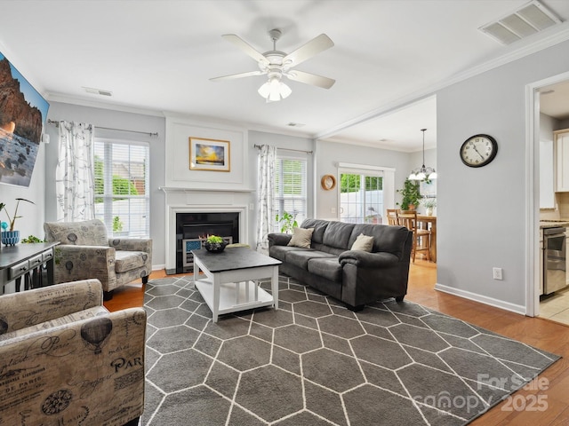 living area featuring dark wood finished floors, visible vents, a ceiling fan, and crown molding