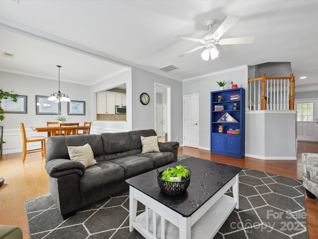 living room with wood finished floors, crown molding, and visible vents