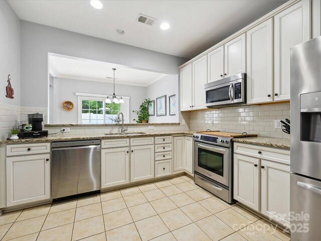 kitchen with appliances with stainless steel finishes, backsplash, a sink, visible vents, and light tile patterned flooring