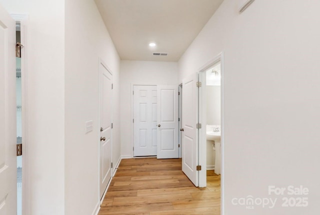 corridor with recessed lighting, visible vents, light wood-type flooring, and baseboards