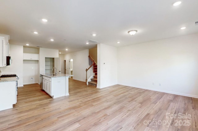kitchen featuring white cabinets, recessed lighting, light wood-type flooring, and a sink