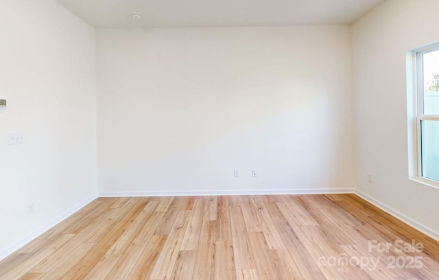 empty room featuring baseboards and light wood-type flooring