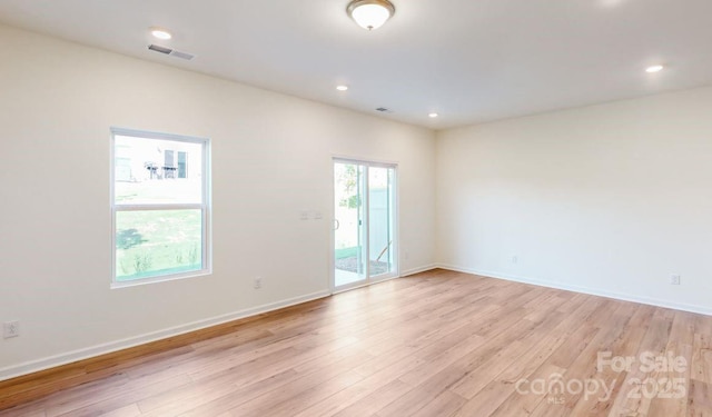 empty room featuring light wood-type flooring, baseboards, and visible vents