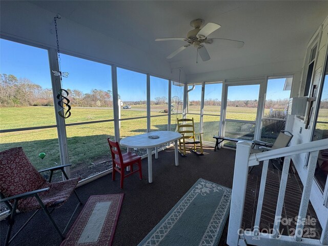 sunroom / solarium with a rural view and a ceiling fan