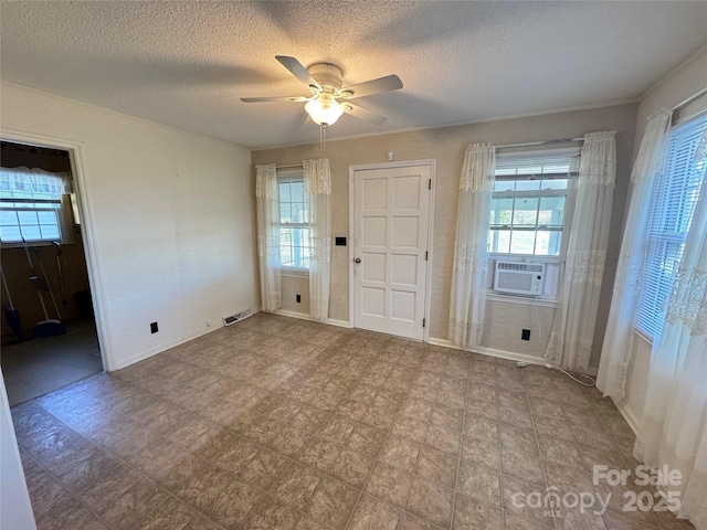 foyer with cooling unit, visible vents, ceiling fan, and a textured ceiling