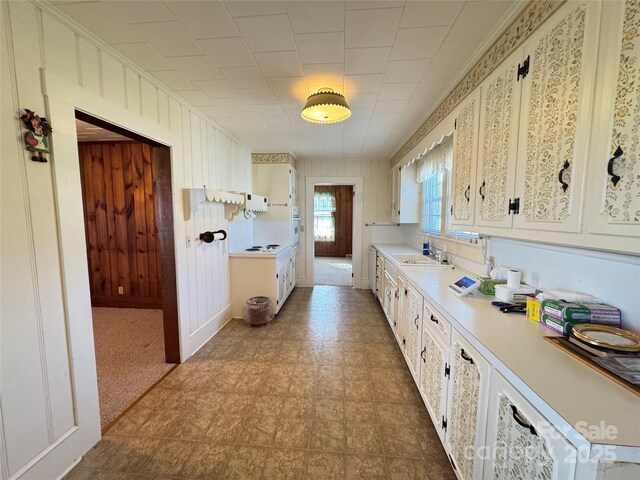 kitchen featuring tile patterned floors, light countertops, electric cooktop, white cabinets, and a sink