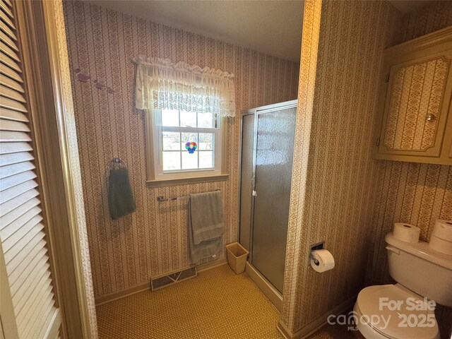 bathroom featuring a stall shower, visible vents, toilet, and wallpapered walls