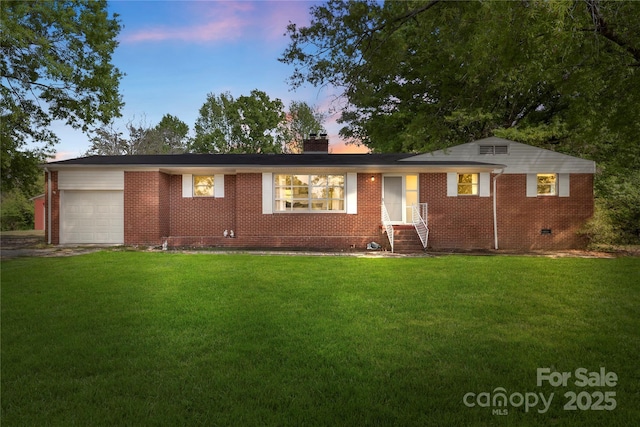 view of front of house featuring crawl space, a chimney, a yard, a garage, and brick siding
