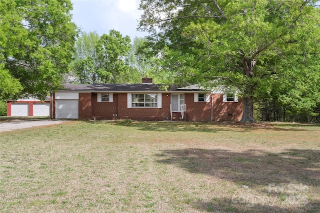 single story home featuring driveway, a chimney, a garage, brick siding, and a front yard