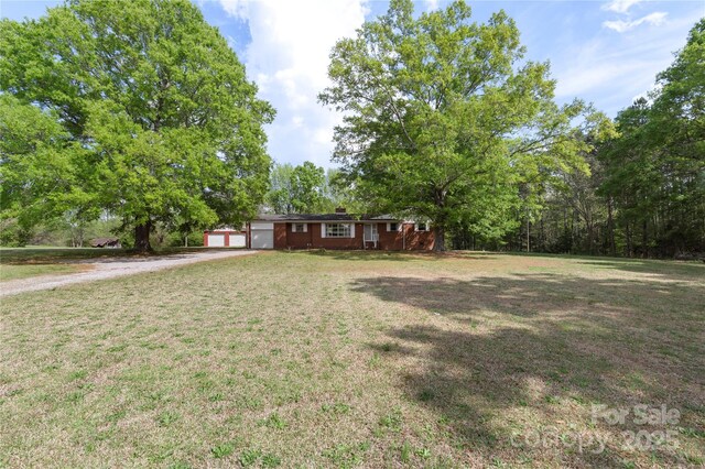 view of yard with a garage and dirt driveway