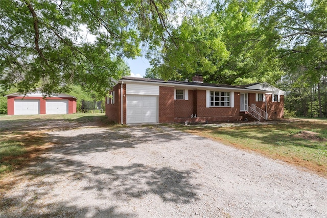 single story home featuring an attached garage, driveway, a chimney, and brick siding