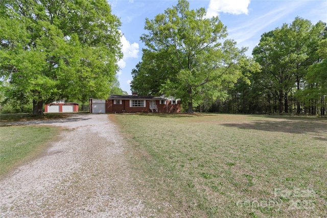 single story home with driveway, an outbuilding, a garage, and a front yard