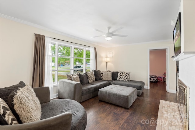living room with crown molding, a fireplace with flush hearth, ceiling fan, baseboards, and dark wood-style flooring