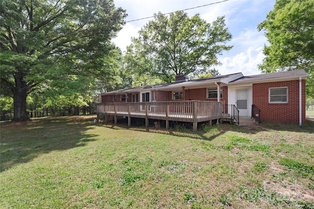 back of house featuring brick siding, a lawn, and a deck