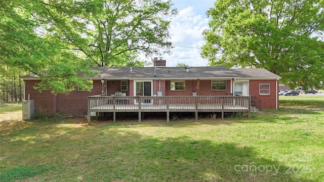 back of house with brick siding, a lawn, a chimney, and a deck