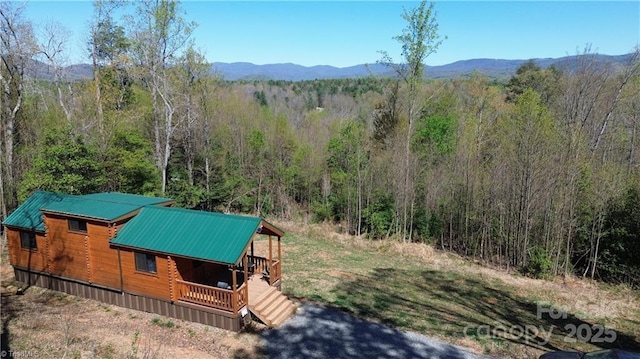 view of property exterior with a forest view, metal roof, a mountain view, and covered porch
