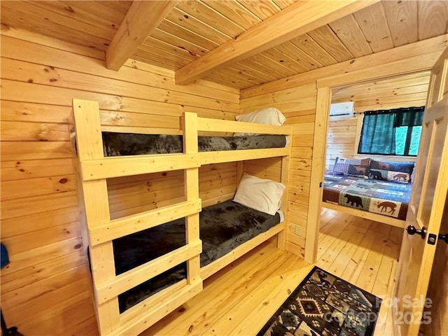 bedroom with wood ceiling, wood walls, beamed ceiling, and hardwood / wood-style floors