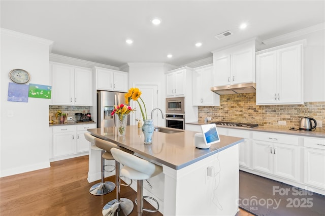 12305 Stinson Ct, Charlotte, NC 28277 - kitchen with visible vents, a sink, under cabinet range hood, stainless steel appliances, and a breakfast bar area