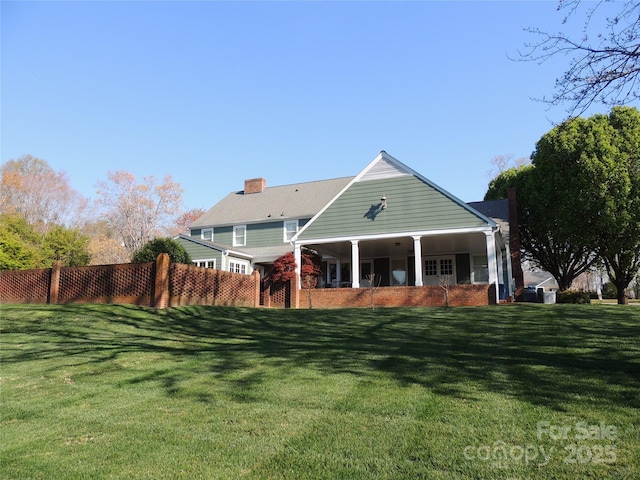 rear view of house with fence and a lawn