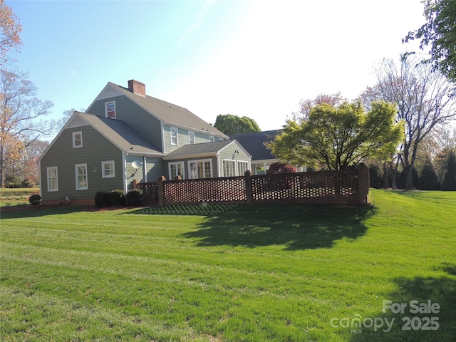 back of house featuring a lawn and a chimney