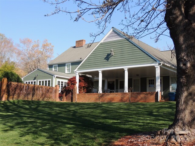 back of property with a chimney, brick siding, and a lawn