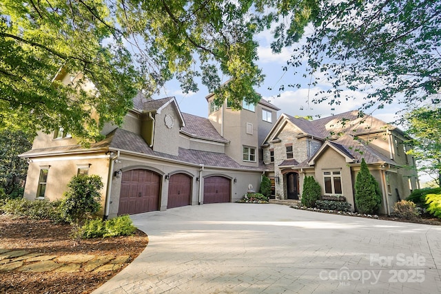view of front facade featuring stucco siding, decorative driveway, and an attached garage