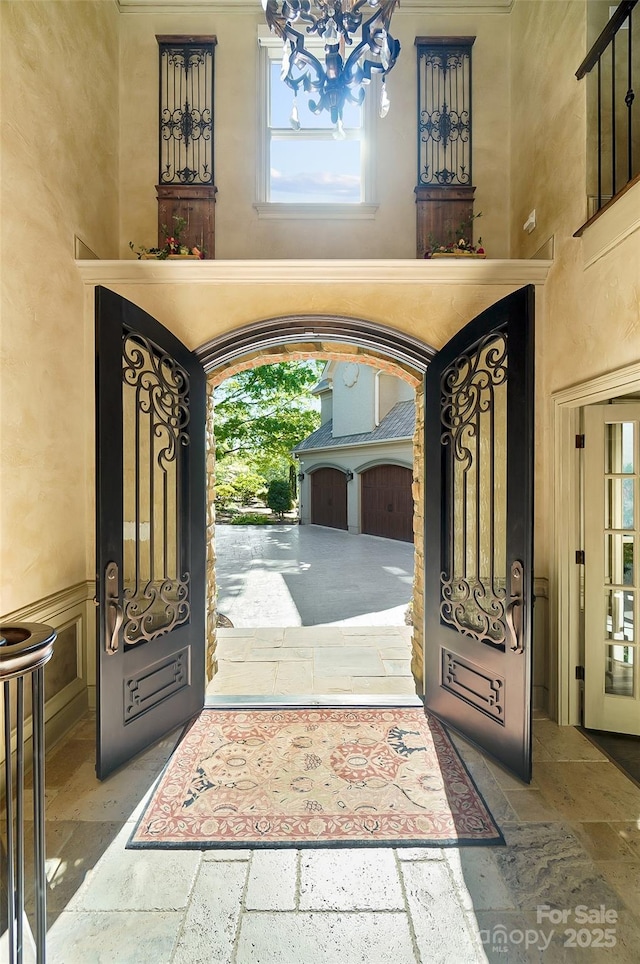 foyer entrance with a chandelier, a healthy amount of sunlight, and stone tile flooring