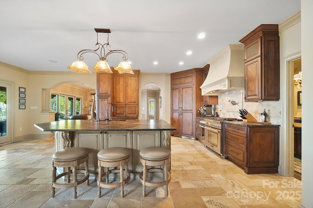 kitchen with arched walkways, stone tile floors, custom range hood, and range with two ovens