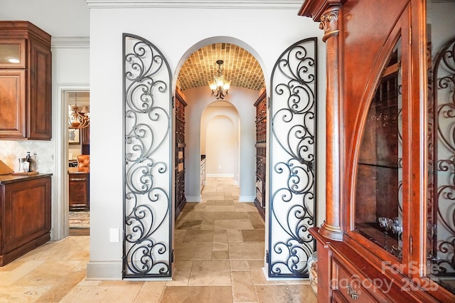 interior space with stone tile flooring, baseboards, arched walkways, and vaulted ceiling