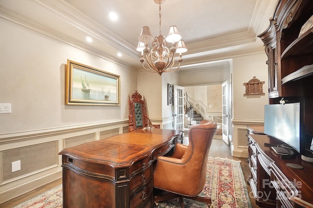 office with a notable chandelier, crown molding, wainscoting, a decorative wall, and wood finished floors