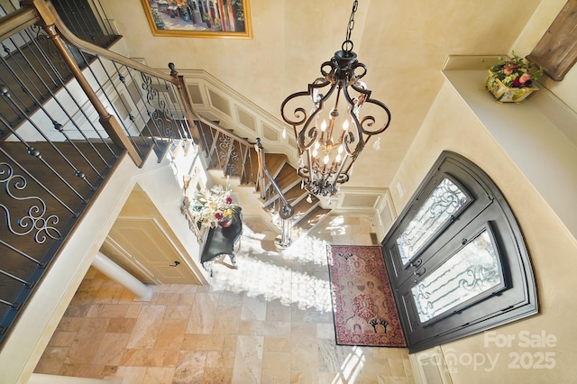 stairway with a chandelier, a towering ceiling, and stone tile flooring